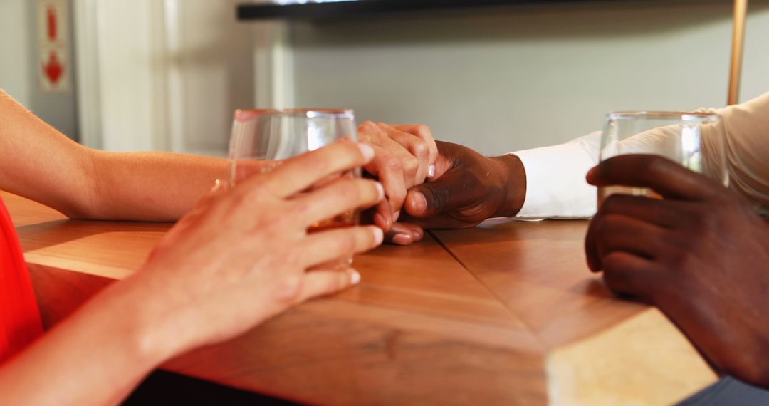 Couple Holding Hands While Enjoying Drinks at Bar Counter