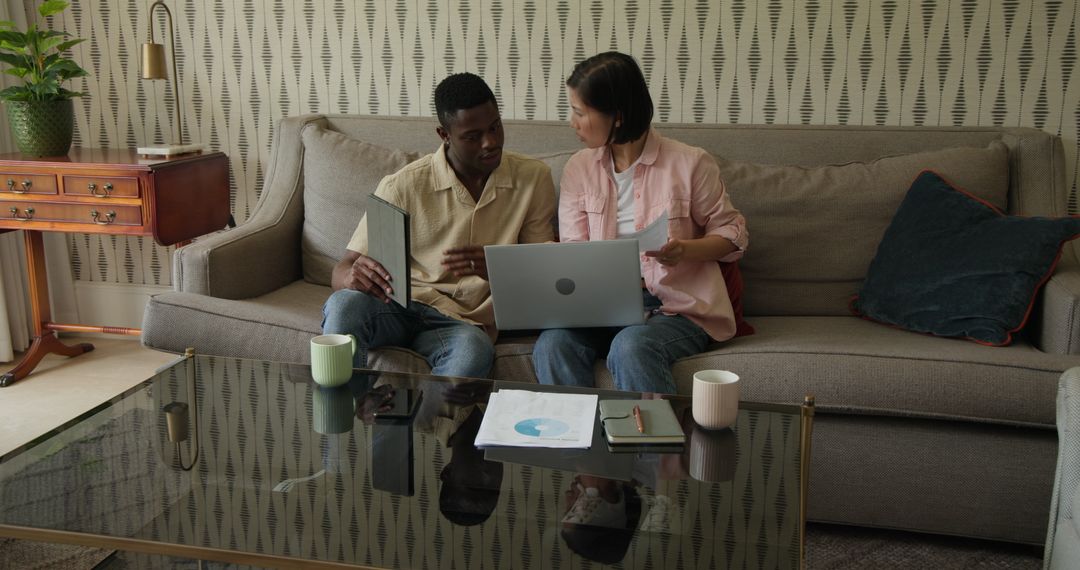 Diverse Team Collaborating on Sofa with Laptop and Documents