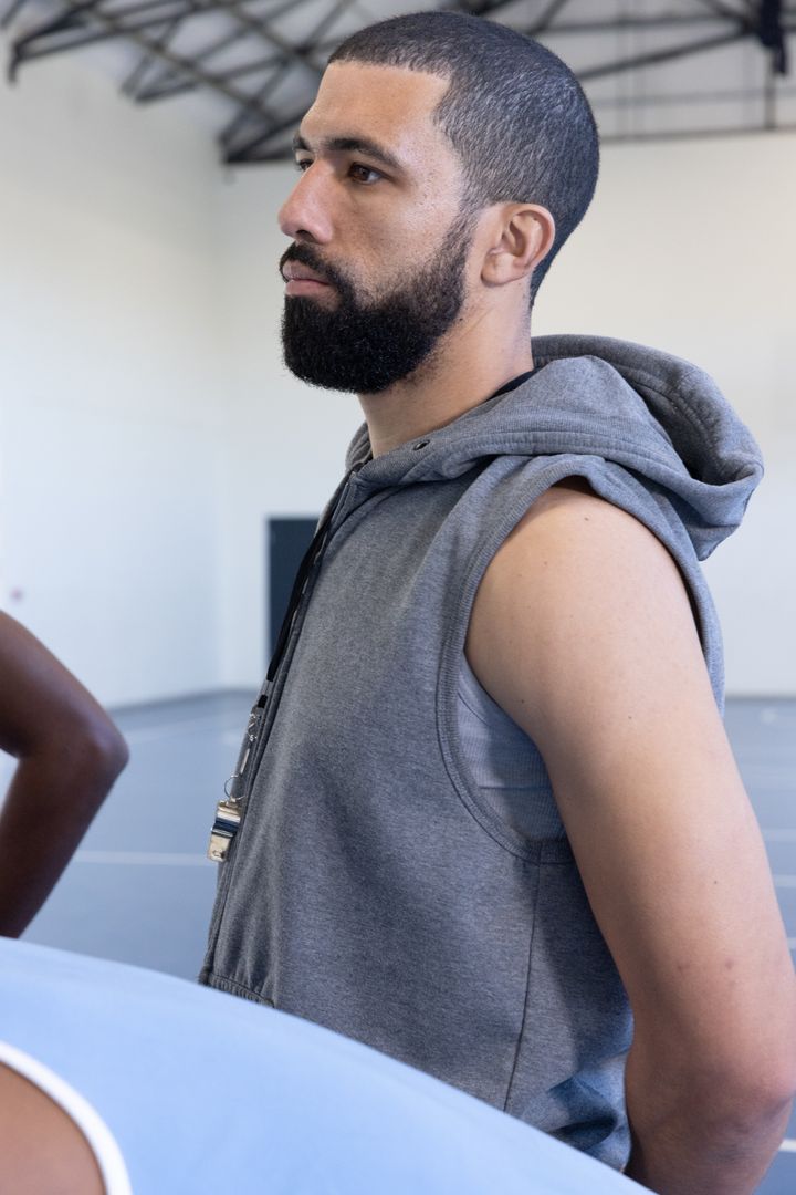 Basketball Coach Motivating Players in Gymnasium