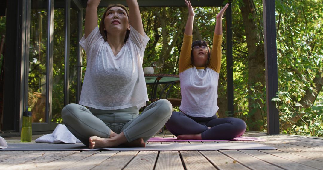 Two Women Practicing Yoga on Outdoor Deck in Forest Setting - Free Images, Stock Photos and Pictures on Pikwizard.com