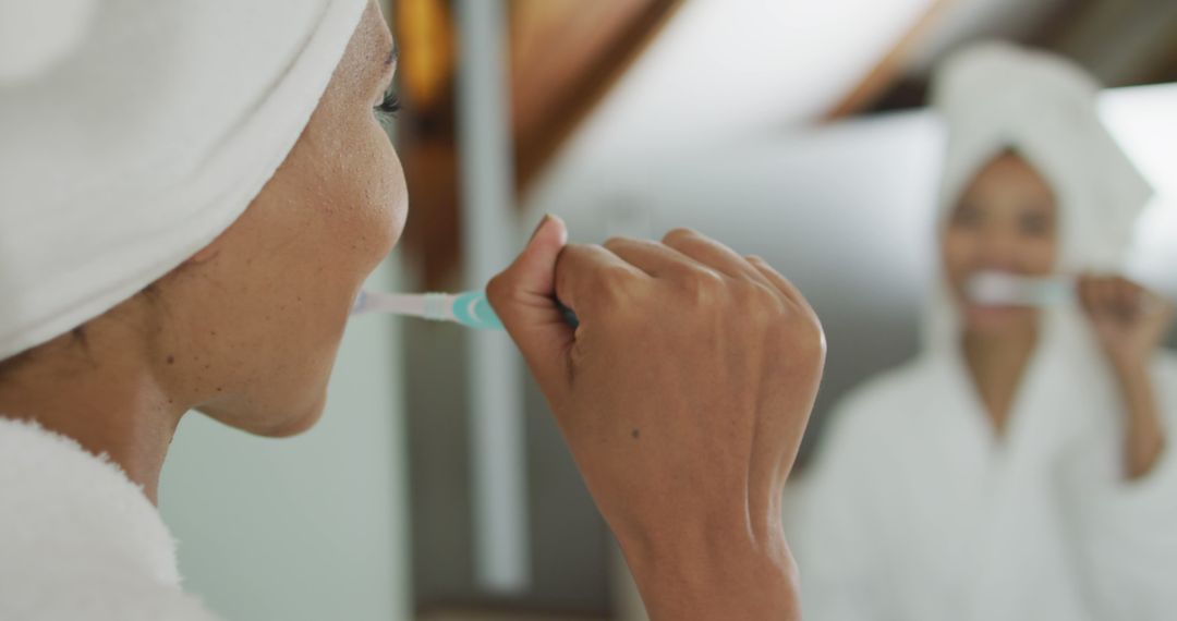 Biracial woman looking at mirror brushing teeth - Free Images, Stock Photos and Pictures on Pikwizard.com