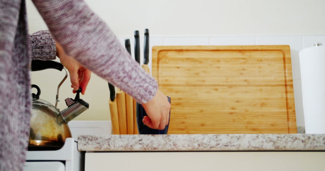 Woman Pouring Tea in Modern Kitchen with Wooden Cutlery Board - Free Images, Stock Photos and Pictures on Pikwizard.com