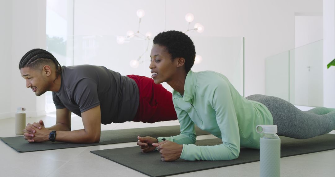 Diverse Exercise Partners Engaging in Plank Hold in Modern Studio