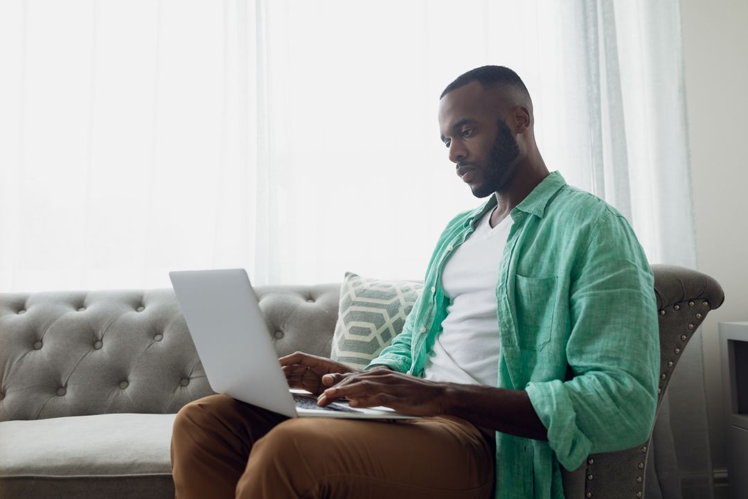 African-American Man Using Laptop on Couch - Free Images, Stock Photos and Pictures on Pikwizard.com
