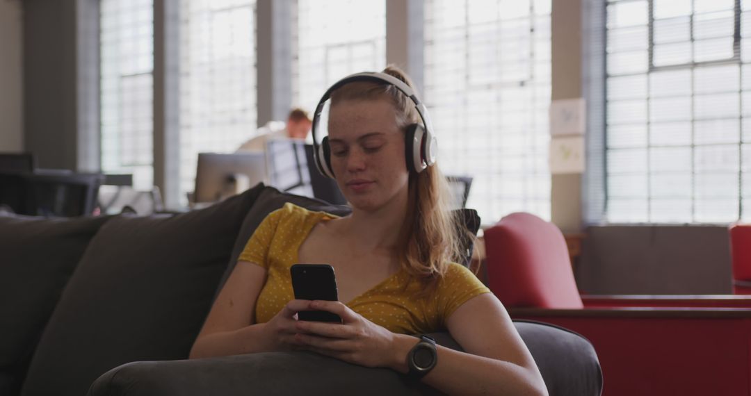 Young Woman Listening to Music with Headphones in Modern Office - Free Images, Stock Photos and Pictures on Pikwizard.com