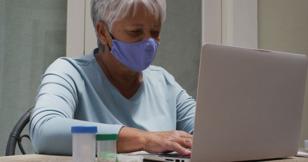 Senior Woman Wearing Face Mask Working on Laptop at Home - Free Images, Stock Photos and Pictures on Pikwizard.com