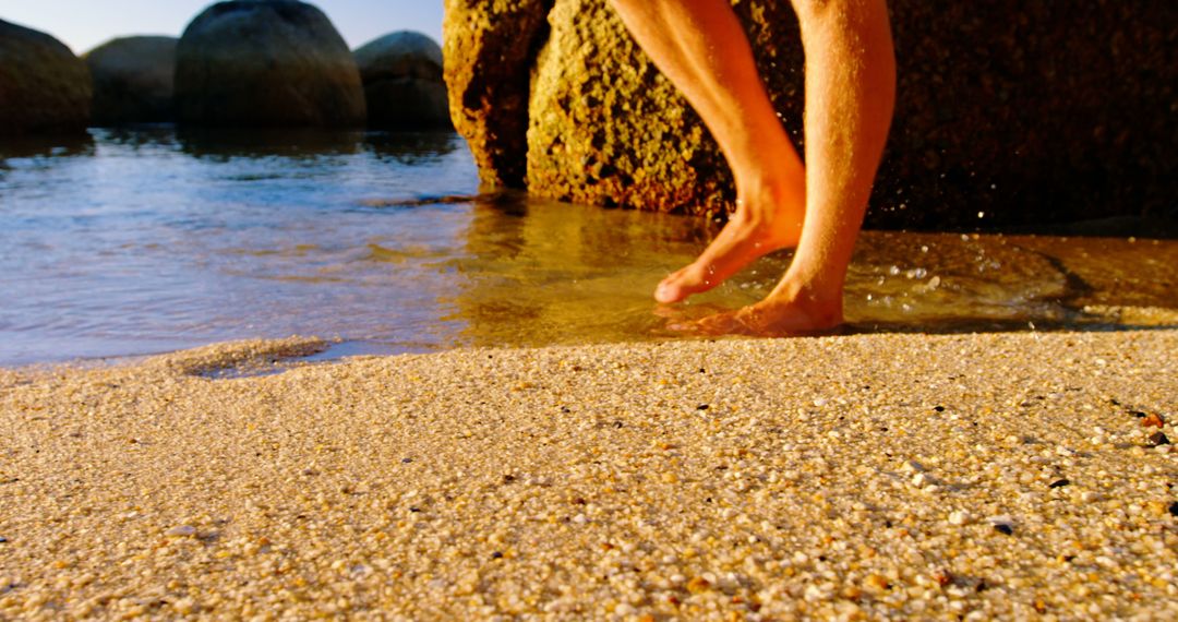 Feet Walking Barefoot On Sandy Beach Near Water And Rocks At Sunset - Free Images, Stock Photos and Pictures on Pikwizard.com