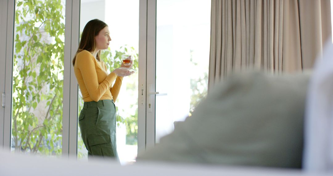 Woman Enjoying Tea and Looking Out Glass Door at Home - Free Images, Stock Photos and Pictures on Pikwizard.com