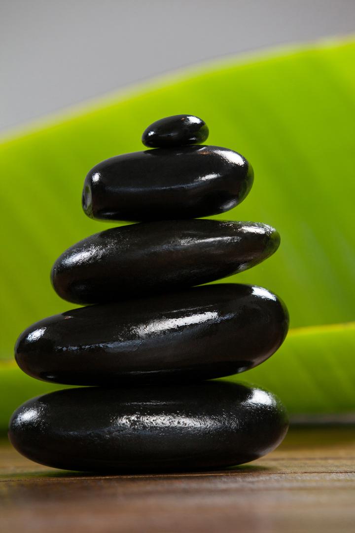 Stacked Black Pebble Stones on Wooden Surface - Free Images, Stock Photos and Pictures on Pikwizard.com