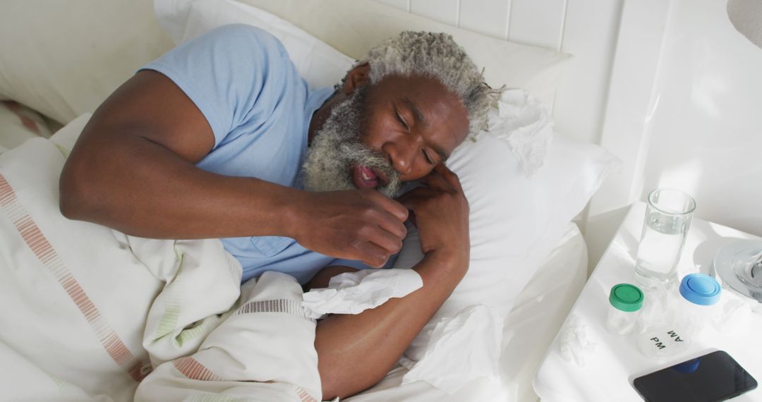 Elderly Man Resting in Bed while Handling Tissue and Medication - Free Images, Stock Photos and Pictures on Pikwizard.com