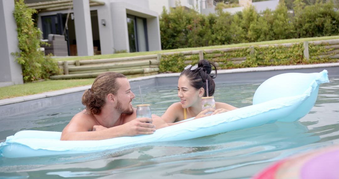 Happy Couple Enjoying Drinks on Inflatable in Pool