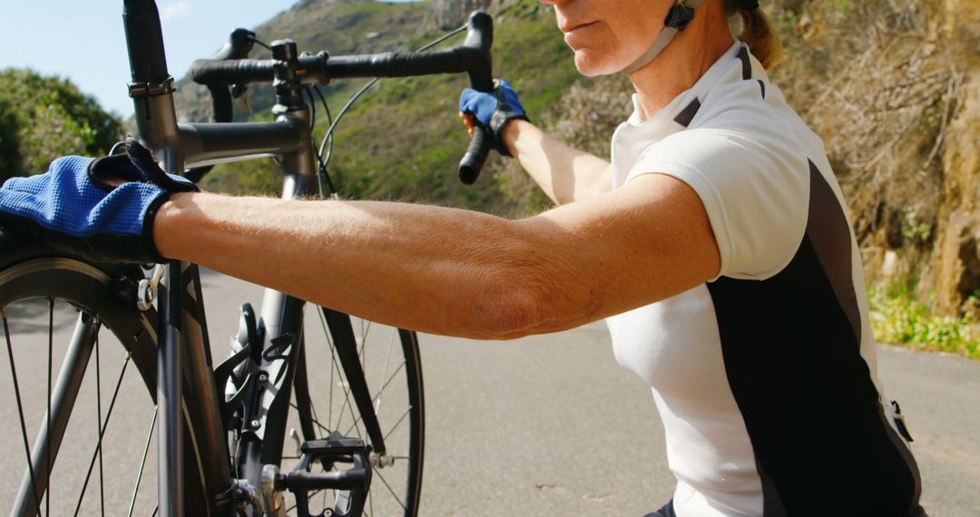 Mature Woman Adjusting Road Bike on Country Road - Free Images, Stock Photos and Pictures on Pikwizard.com