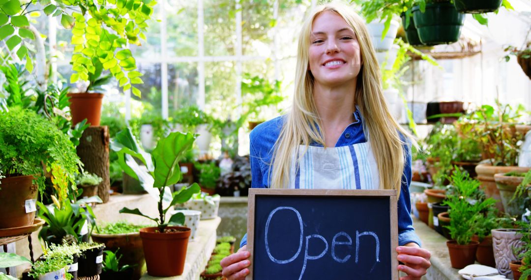 Smiling Woman Holding Open Sign in Plant Nursery - Free Images, Stock Photos and Pictures on Pikwizard.com