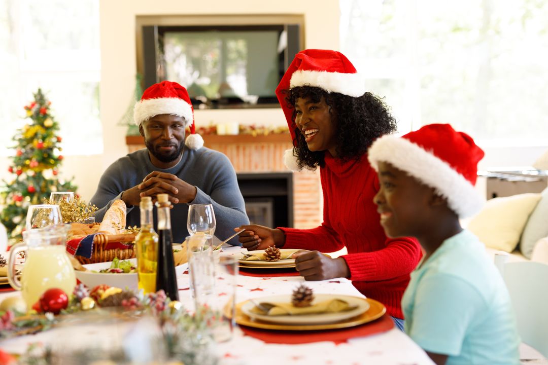 Front view of an african-american family enjoying their christmas dinner all wearing santa hats - Free Images, Stock Photos and Pictures on Pikwizard.com