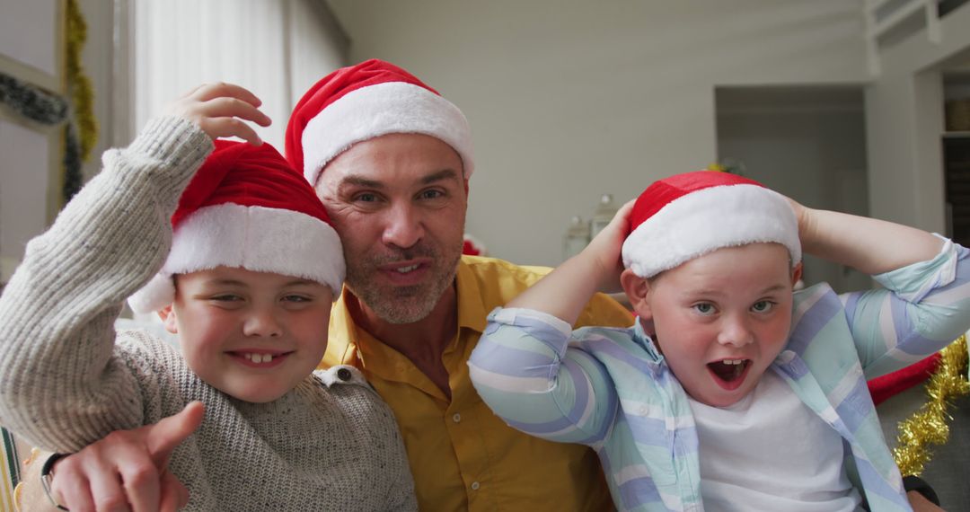 A festive family portrait captures a smiling father and sons in Santa hats celebrating Christmas. - Free Images, Stock Photos and Pictures on Pikwizard.com