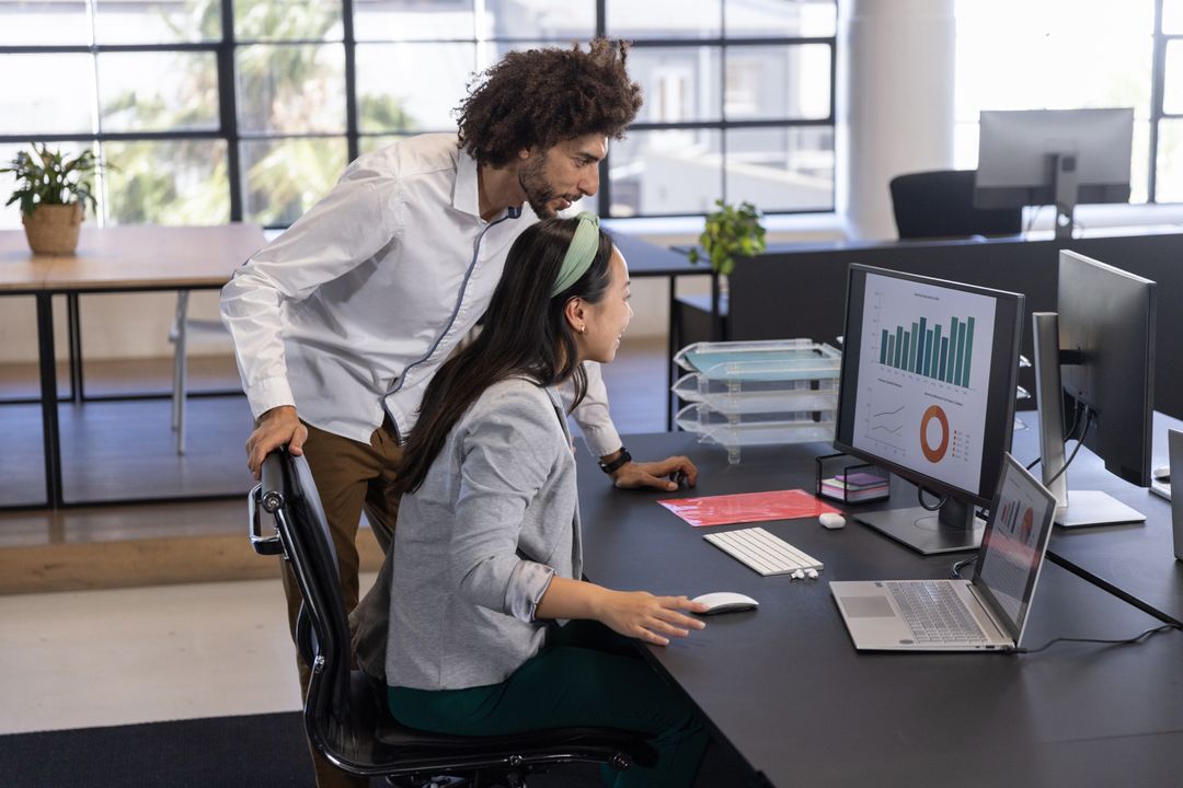 Team Analyzing Financial Data on Dual Monitors in Modern Office