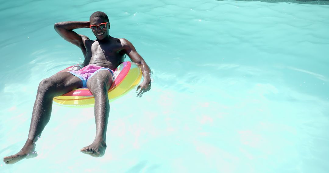 Man Floating Relaxedly on Pink Inflatable in Bright Pool
