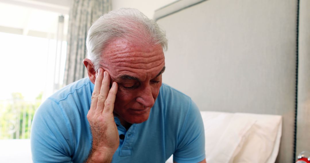 Senior Man Sitting on Bed Holding Head Looking Worried - Free Images, Stock Photos and Pictures on Pikwizard.com