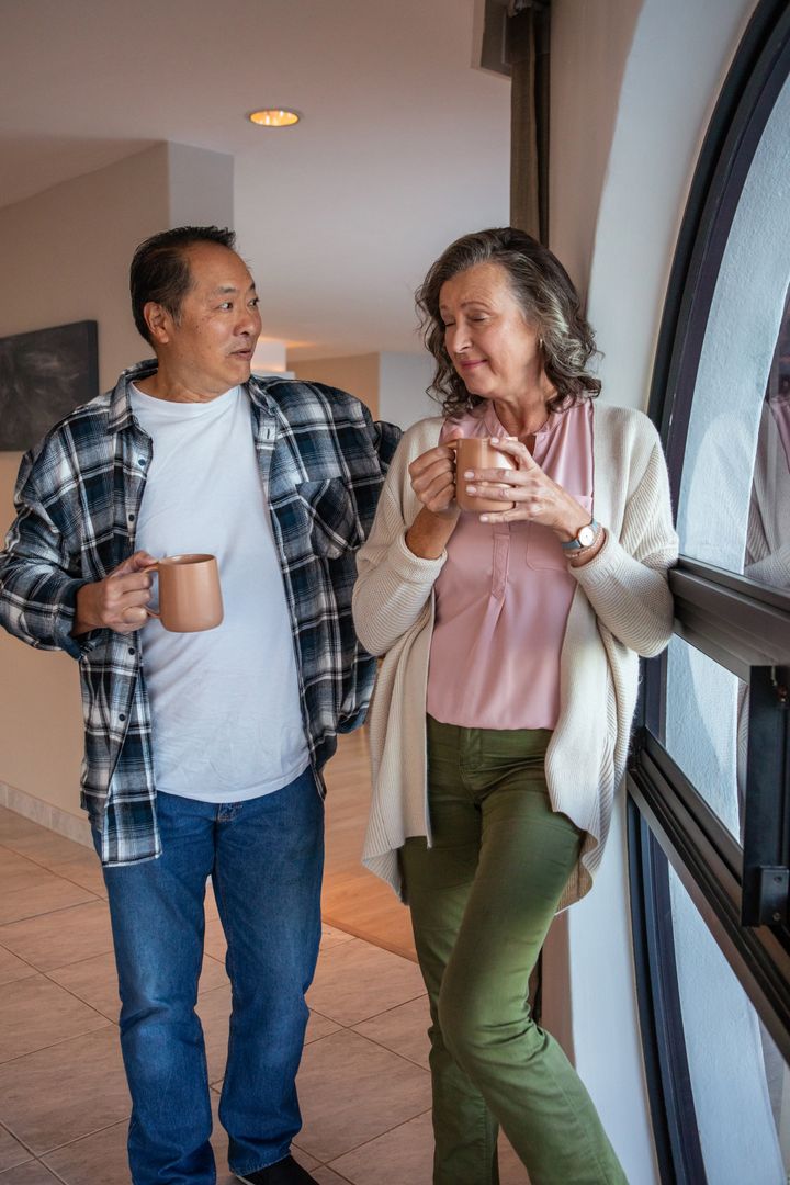 Senior Couple Enjoying Coffee Near Arched Window in Modern Home