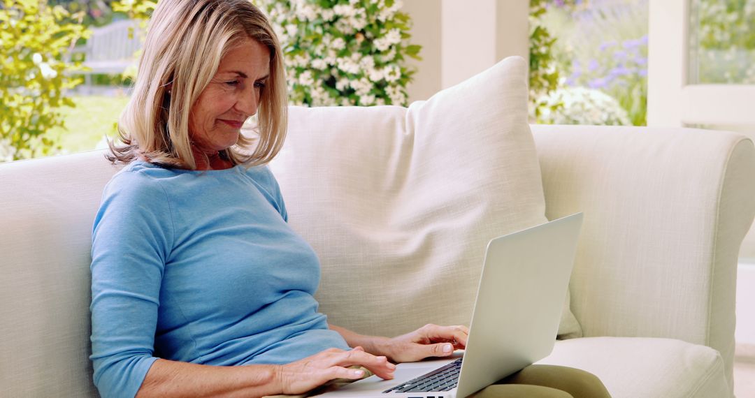 Senior Woman Using Laptop on Sofa in Bright Living Room - Free Images, Stock Photos and Pictures on Pikwizard.com