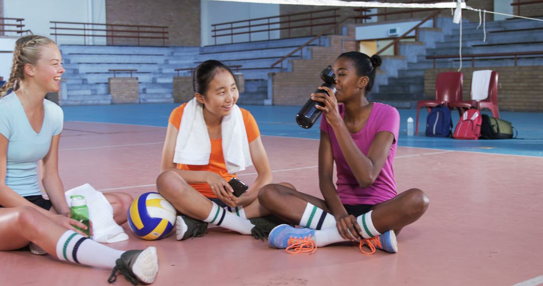 Three Female Volleyball Players Resting and Hydrating in Gym - Free Images, Stock Photos and Pictures on Pikwizard.com