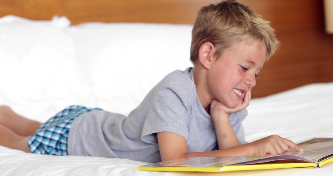 Young Boy Reading Enthusiastically on Bed - Free Images, Stock Photos and Pictures on Pikwizard.com