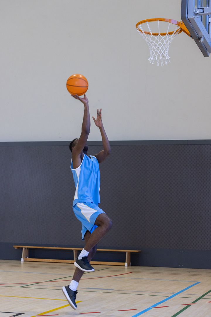 Energetic Basketball Player Making Layup in Gym