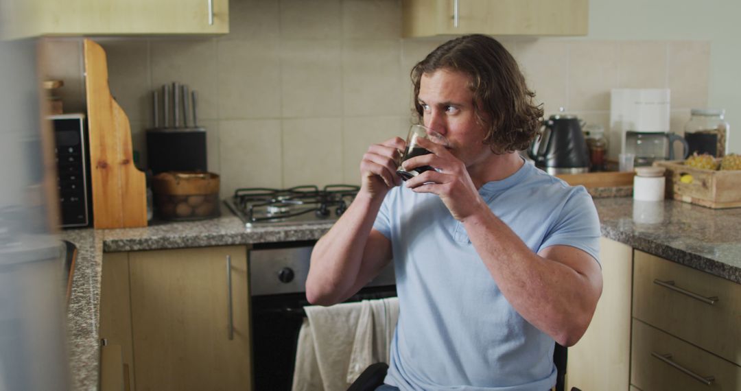 Man with long hair drinking coffee in kitchen - Free Images, Stock Photos and Pictures on Pikwizard.com