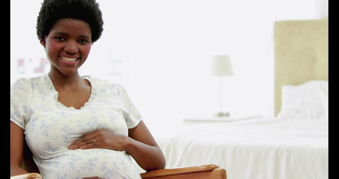 Smiling Pregnant Woman Sitting in Bedroom - Free Images, Stock Photos and Pictures on Pikwizard.com