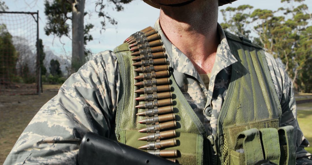 Uniformed Soldier Holding Gun with Ammunition Belt Over Shoulder in Outdoor Setting - Free Images, Stock Photos and Pictures on Pikwizard.com