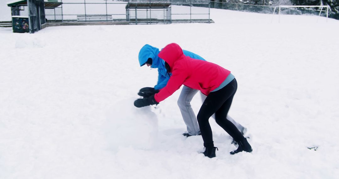 Couple Building Snowman During Winter Outdoors - Free Images, Stock Photos and Pictures on Pikwizard.com