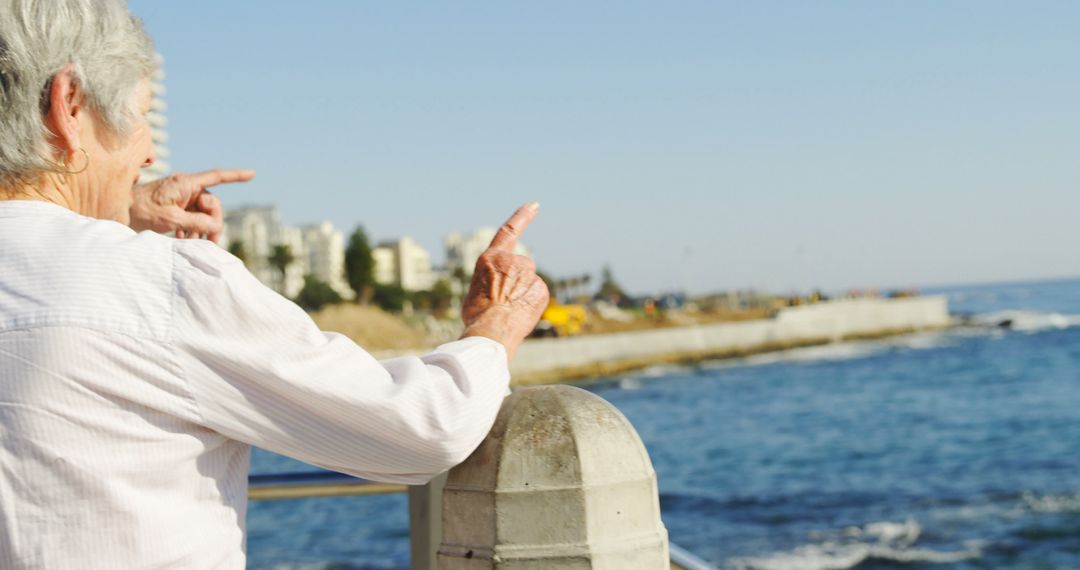 Senior Woman Pointing Towards Ocean, Enjoying Beach View - Free Images, Stock Photos and Pictures on Pikwizard.com