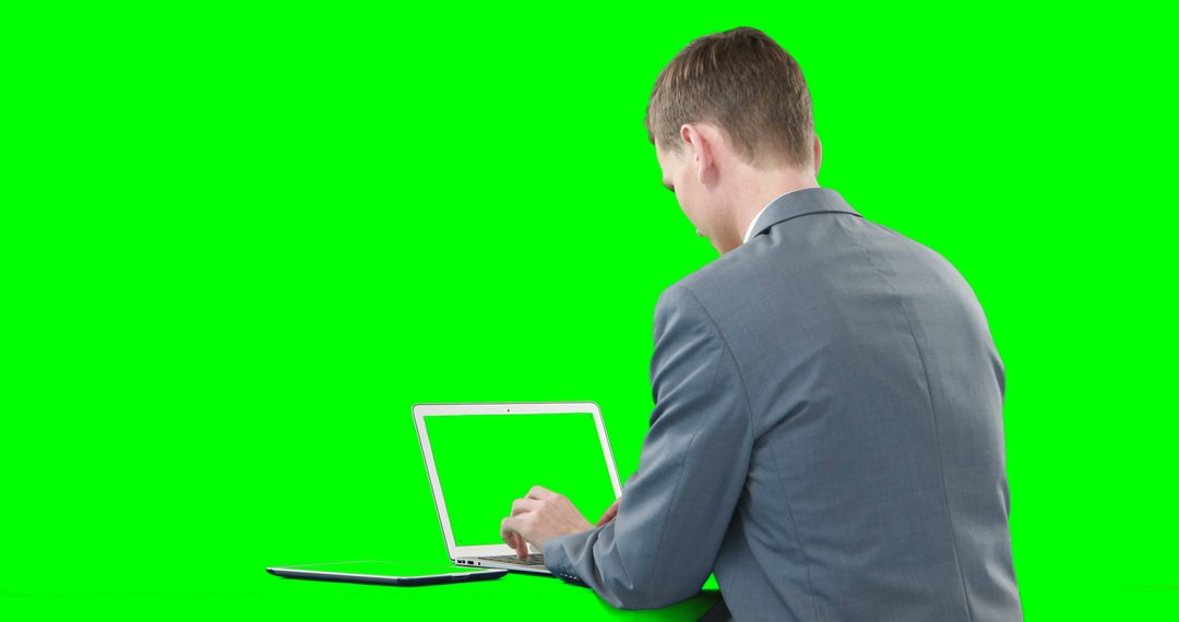 Professional Businessman Using Laptop Against Green Background - Free Images, Stock Photos and Pictures on Pikwizard.com