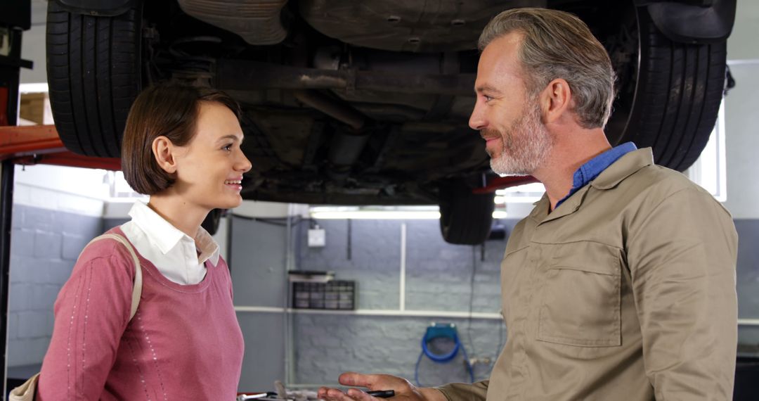 Smiling Mechanic Discussing Vehicle Repair with Female Customer at Garage - Free Images, Stock Photos and Pictures on Pikwizard.com