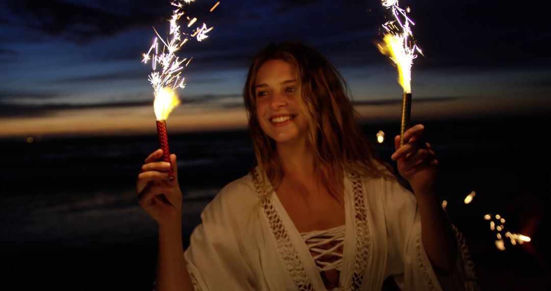 Joyful Woman with Sparklers Enjoying Beach at Dusk - Free Images, Stock Photos and Pictures on Pikwizard.com