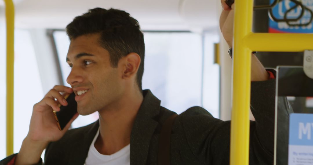 Young man smiling while talking on phone in public transport - Free Images, Stock Photos and Pictures on Pikwizard.com