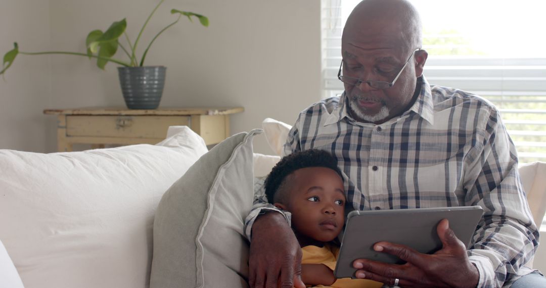 African American Grandfather Reading Book to Grandchild on Sofa - Free Images, Stock Photos and Pictures on Pikwizard.com