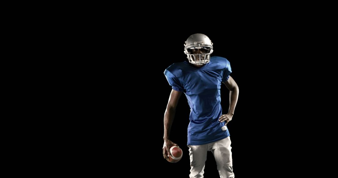 American Football Player Holding Ball Against Black Background - Free Images, Stock Photos and Pictures on Pikwizard.com