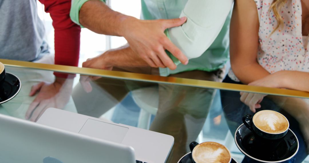 Friends Enjoying Coffee and Laptop Interaction at Cafe Table