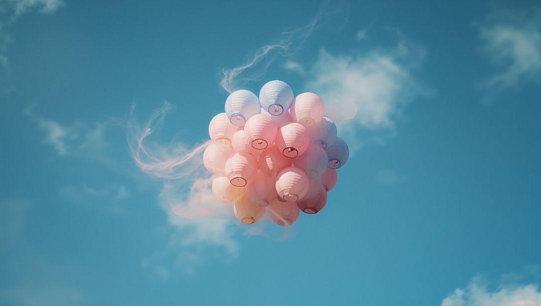 Cluster of Pastel Lanterns Floating in Blue Sky with Smoke Trails