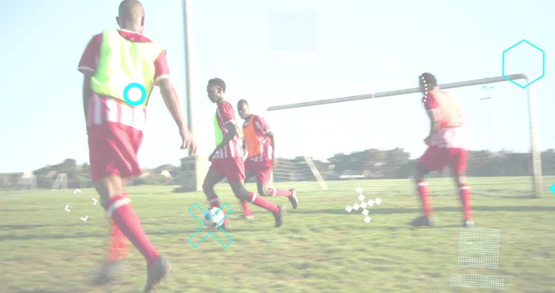 Youth soccer players converging on ball near goalpost wearing neon bibs and red jerseys
