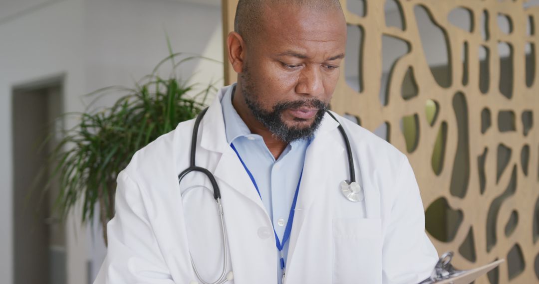 African American Doctor Reviewing Patient Chart Wearing Stethoscope - Free Images, Stock Photos and Pictures on Pikwizard.com