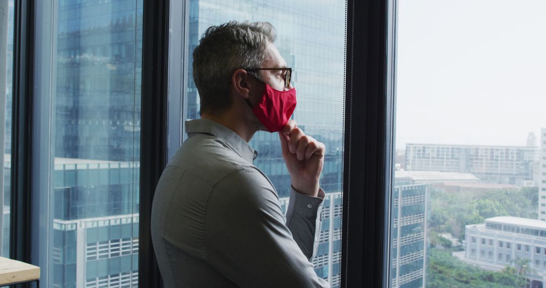 Contemplative Man Wearing Face Mask Looking Out Office Window - Free Images, Stock Photos and Pictures on Pikwizard.com