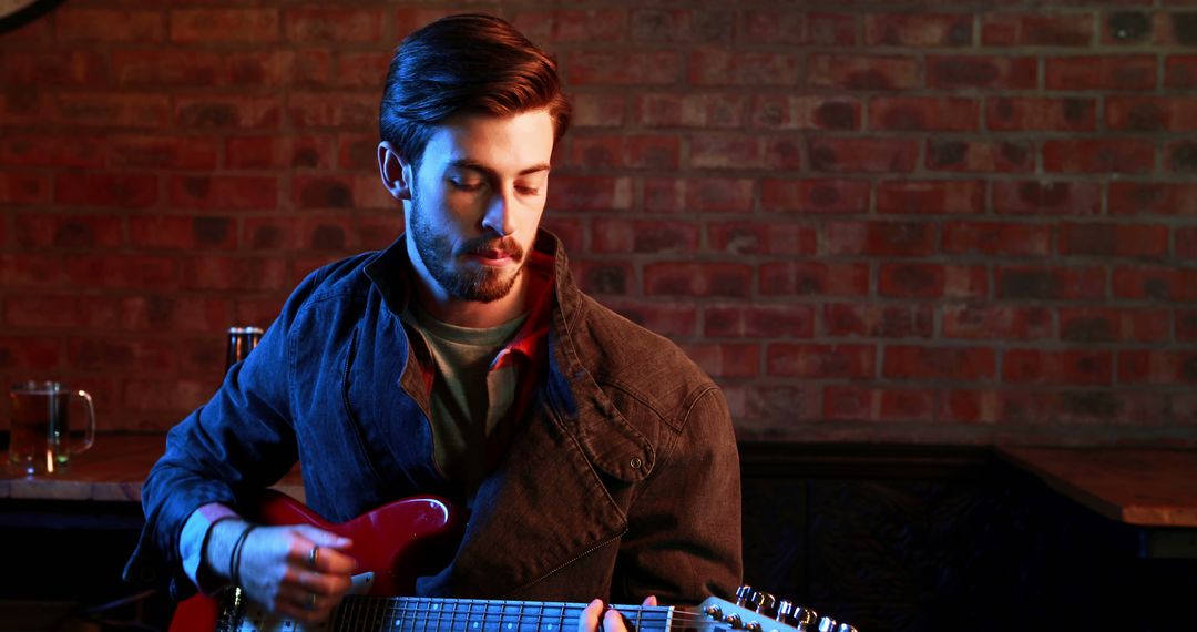 Young Man Playing Electric Guitar in Dimly Lit Room - Free Images, Stock Photos and Pictures on Pikwizard.com