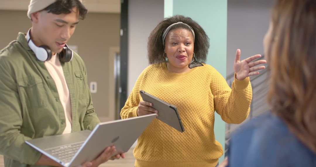 Diverse team collaborating in modern coworking space, woman leading with tablet