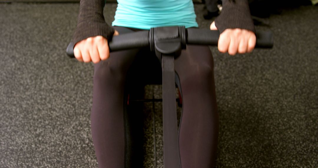 Focused Female Exercising on Rowing Machine in Gym
