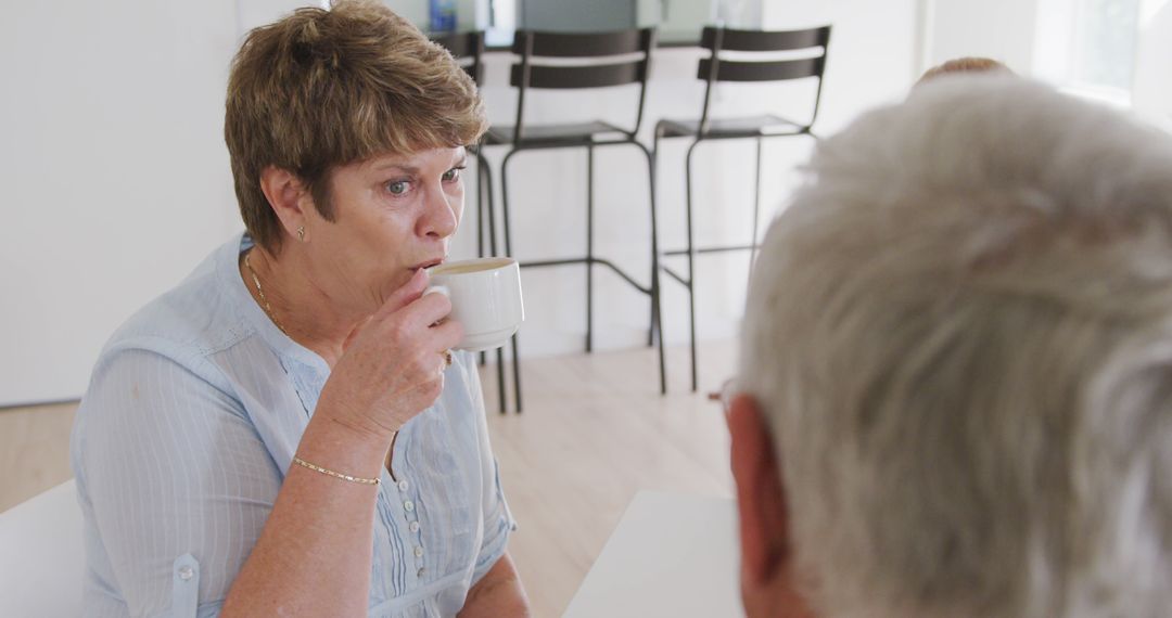 Elderly Woman Drinking Coffee While Conversing at Home - Free Images, Stock Photos and Pictures on Pikwizard.com