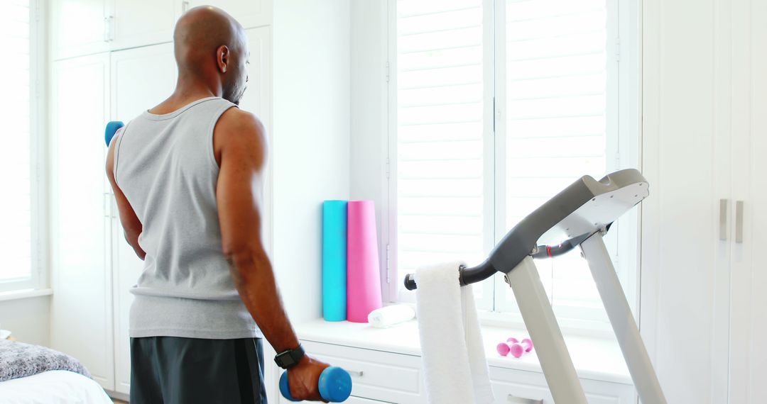 Man Exercising at Home with Dumbbells and Treadmill - Free Images, Stock Photos and Pictures on Pikwizard.com