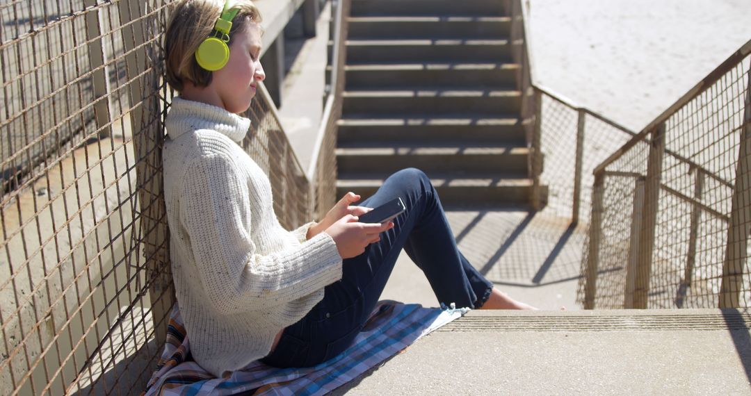 Teen Relaxing on Outdoor Steps with Headphones - Free Images, Stock Photos and Pictures on Pikwizard.com