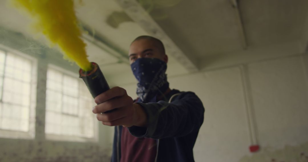 Masked Individual Holding Smoke Bomb with Yellow Fume in Abandoned Building - Free Images, Stock Photos and Pictures on Pikwizard.com